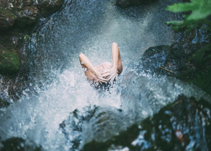 Frau unter Wasserfall
