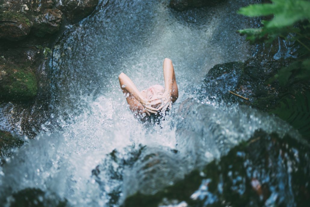 Frau unter Wasserfall